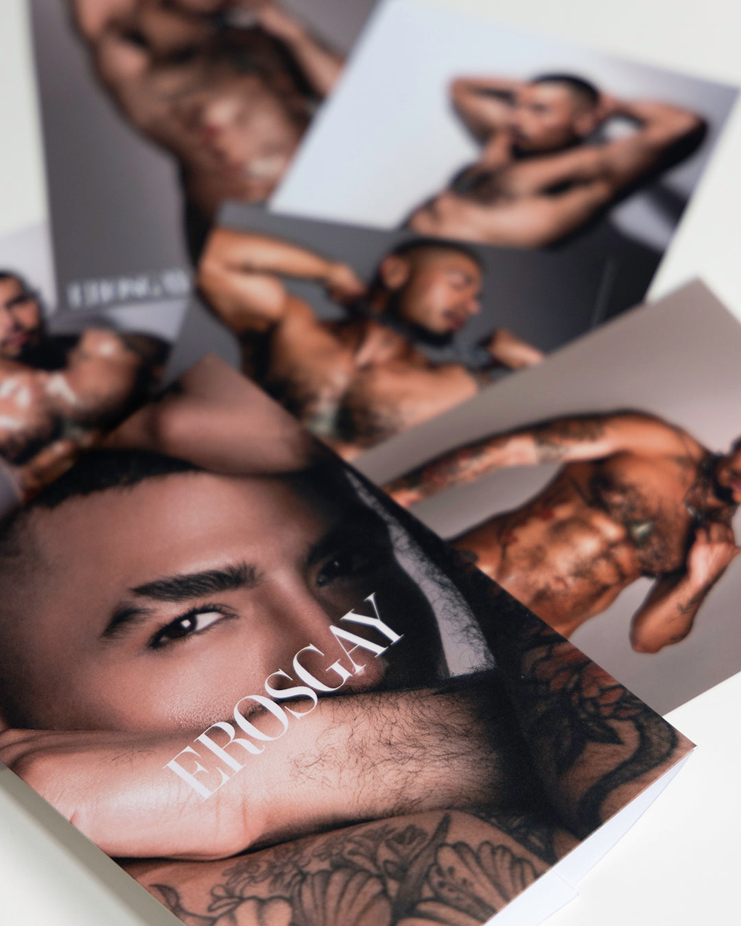 SixPack de Yahir x ErosGay, en la imagen la portada del sobre de la msima coleccion con las 6 fotos impresas desenfocadas en el fondo. 