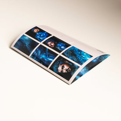 Vista trasera del sobre del producto Sixpack de ErosGay (colección Oráculo, modelo FelixFox), mostrando el reverso con la cuadrícula de 6 miniaturas/ventanas de la serie en tonos azules, sobre una superficie clara