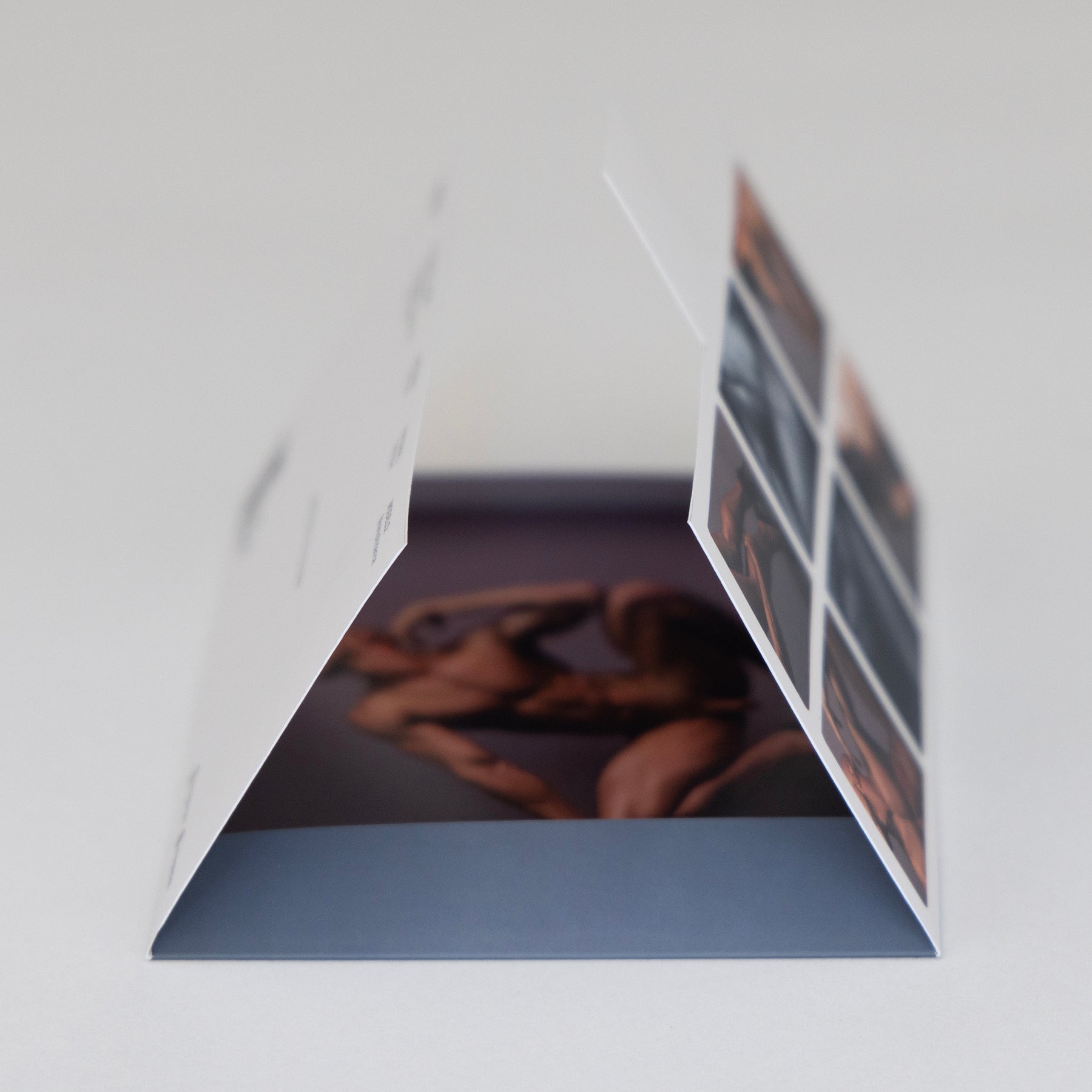 Sobre del Sixpack Kevin de ErosGay abierto en perspectiva, mostrando el interior con una fotografía impresa dentro; se aprecia el panel lateral con miniaturas del contenido