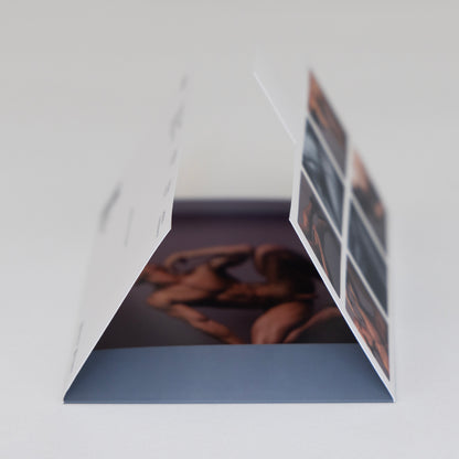 Sobre del Sixpack Kevin de ErosGay abierto en perspectiva, mostrando el interior con una fotografía impresa dentro; se aprecia el panel lateral con miniaturas del contenido