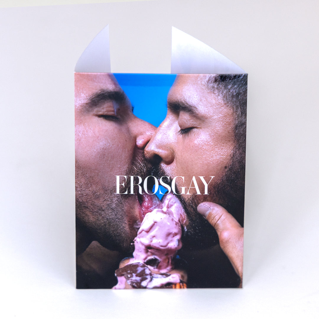 Sobre del sixpack ‘Verano Mexicano’ de ErosGay fotografiado de frente sobre fondo claro. La portada muestra un close-up íntimo de dos hombres besándose y compartiendo un helado, con el logotipo ‘EROSGAY’ centrado en tipografía blanca. En la parte superior se ven las dos solapas del sobre abiertas