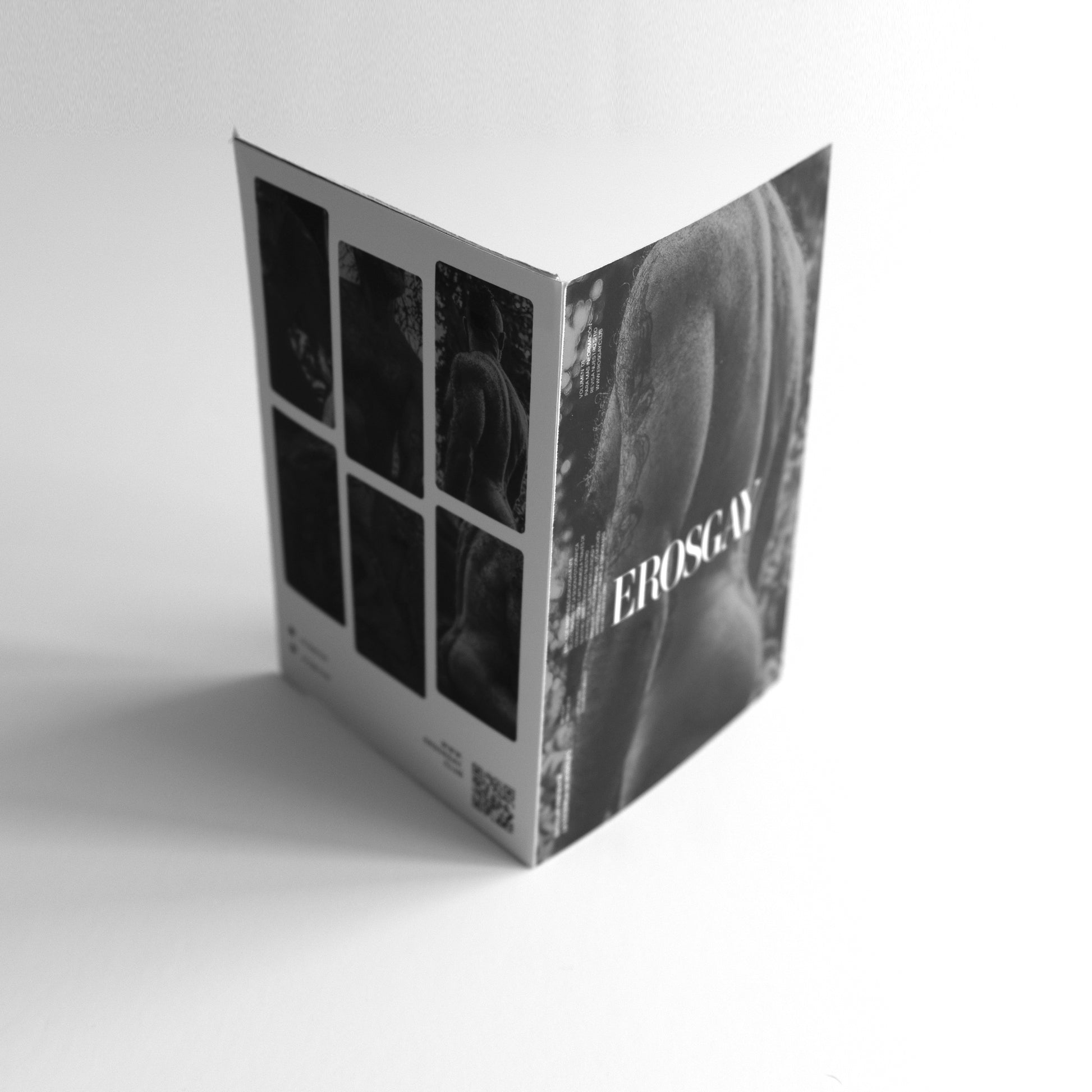 Empaque del Six Pack Lobo Vol. 1 de ErosGay en blanco y negro; vista en ángulo con el logo “EROSGAY” sobre la silueta de un modelo de espaldas, y al reverso una cuadrícula con seis imágenes y un código QR.
