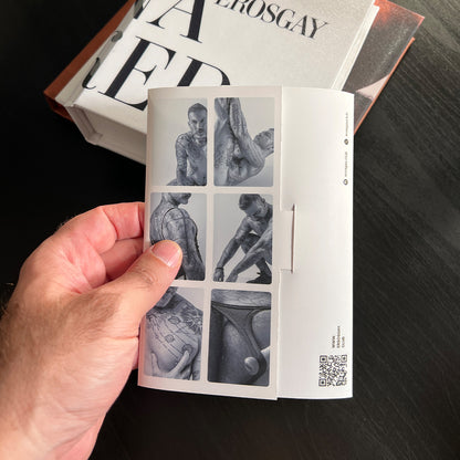 Una mano sosteniendo el sobre del Sixpack de Jose de ErosGay para mostrar referencia de tamaño; en la parte trasera se ve un mosaico de seis imágenes en blanco y negro y un código QR, sobre una mesa oscura.
Alt text (más corto):