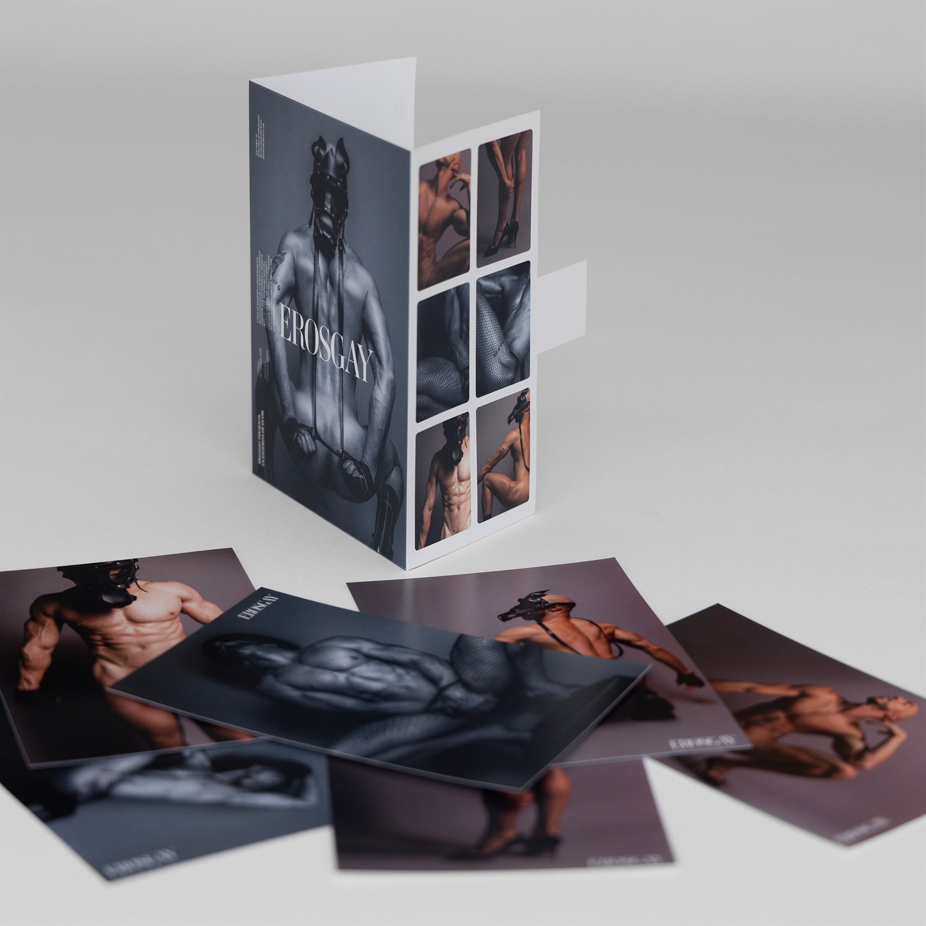 Packshot del Sixpack Kevin de ErosGay: el sobre desplegable de pie y las seis fotos impresas acomodadas alrededor sobre fondo neutro