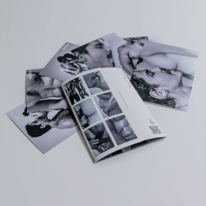 Vista trasera del sobre del Sixpack de ErosGay en blanco y negro, abierto y colocado sobre una superficie clara; a un lado se ven las seis fotos del sixpack extendidas y superpuestas, con detalles del reverso del sobre y un código QR visible.